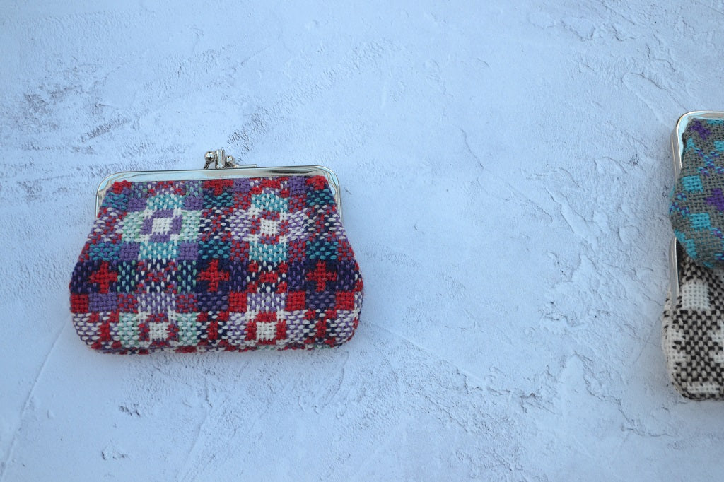 Colorful woven clutch bag on a textured white surface