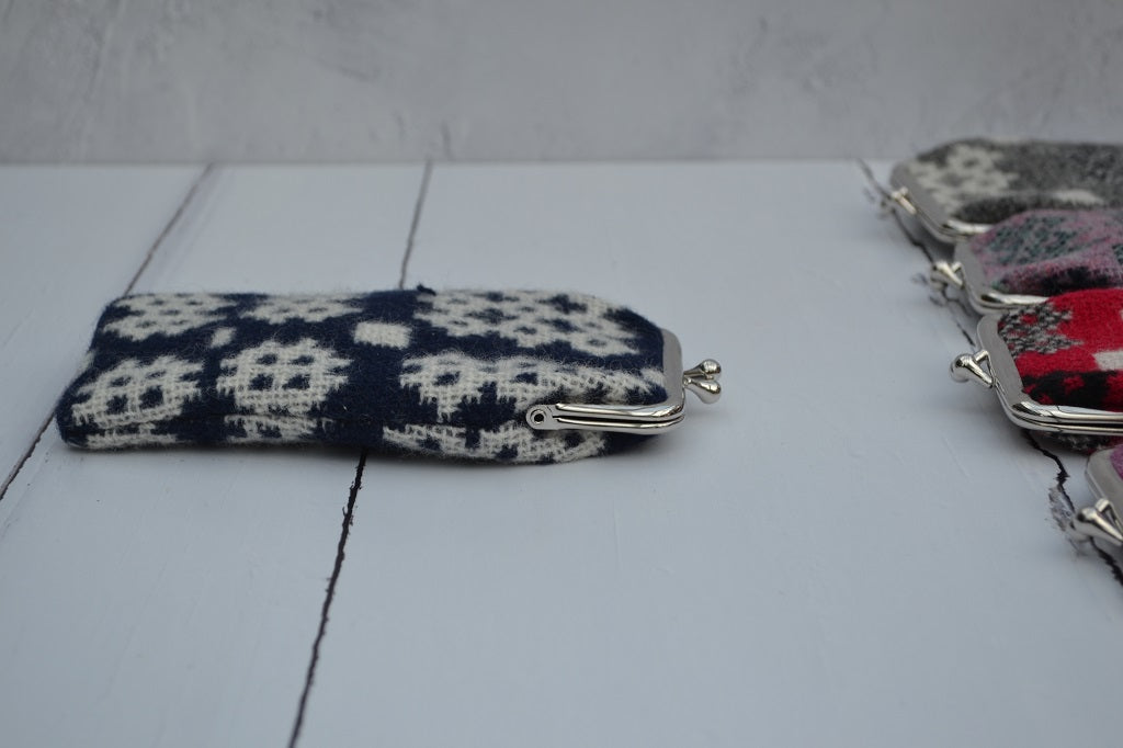 A collection of Welsh tapestry eye glasses cases with metal clasp, displayed on a white surface. The cases feature various traditional Welsh patterns and colours.