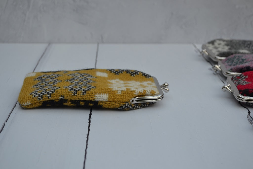 A collection of Welsh tapestry eye glasses cases with metal clasp, displayed on a white surface. The cases feature various traditional Welsh patterns and colours   