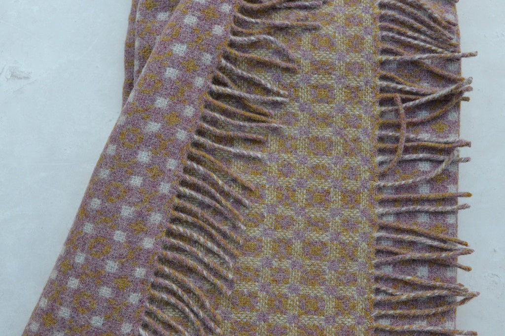 Heather Welsh blanket. Textile with a patterned design and frayed edge on a white background