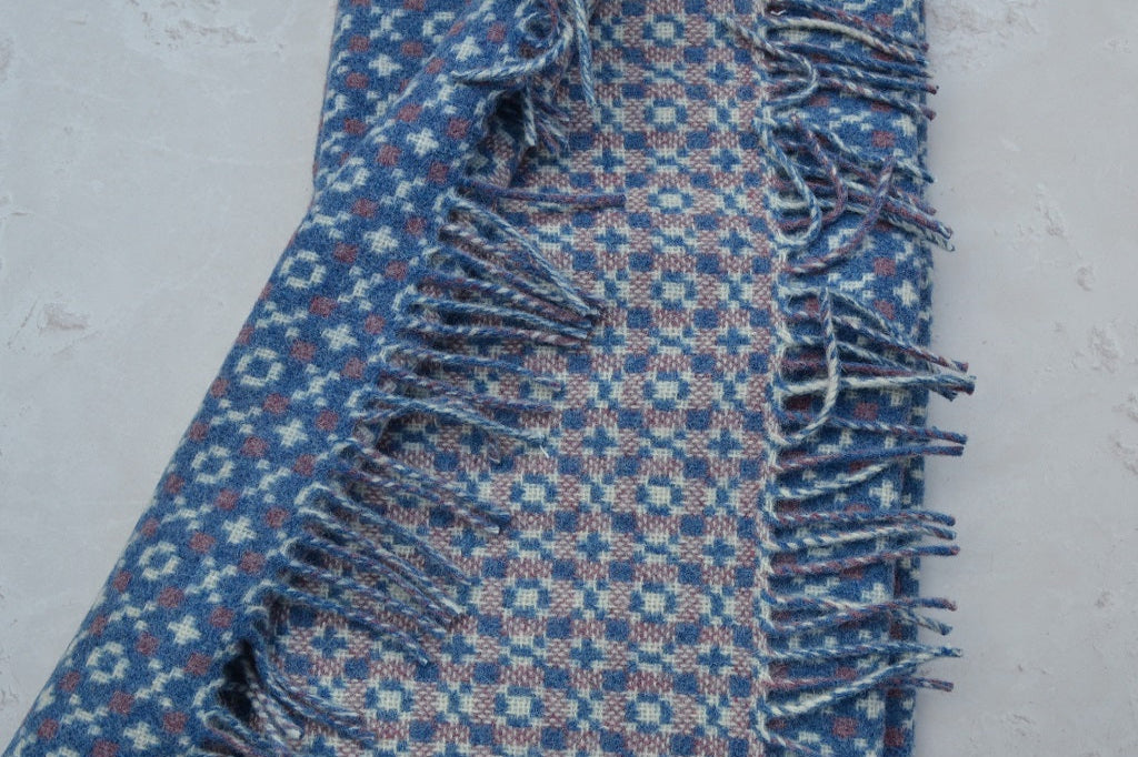 Welsh blanket, Gorwel. Blue patterned fabric with fringes on a light gray background