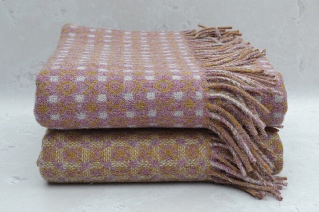 Heather Welsh Blanket. Stacked woven blankets with a checkered pattern on a light gray background